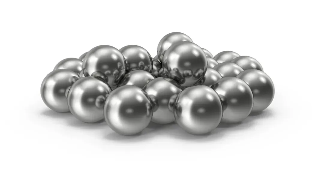 A pile of polished steel shot pellets on a white background